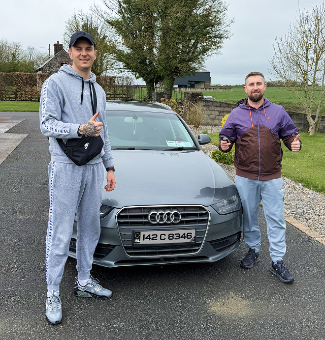 Two happy MNTVLSAUTO customers next to an inspected Audi